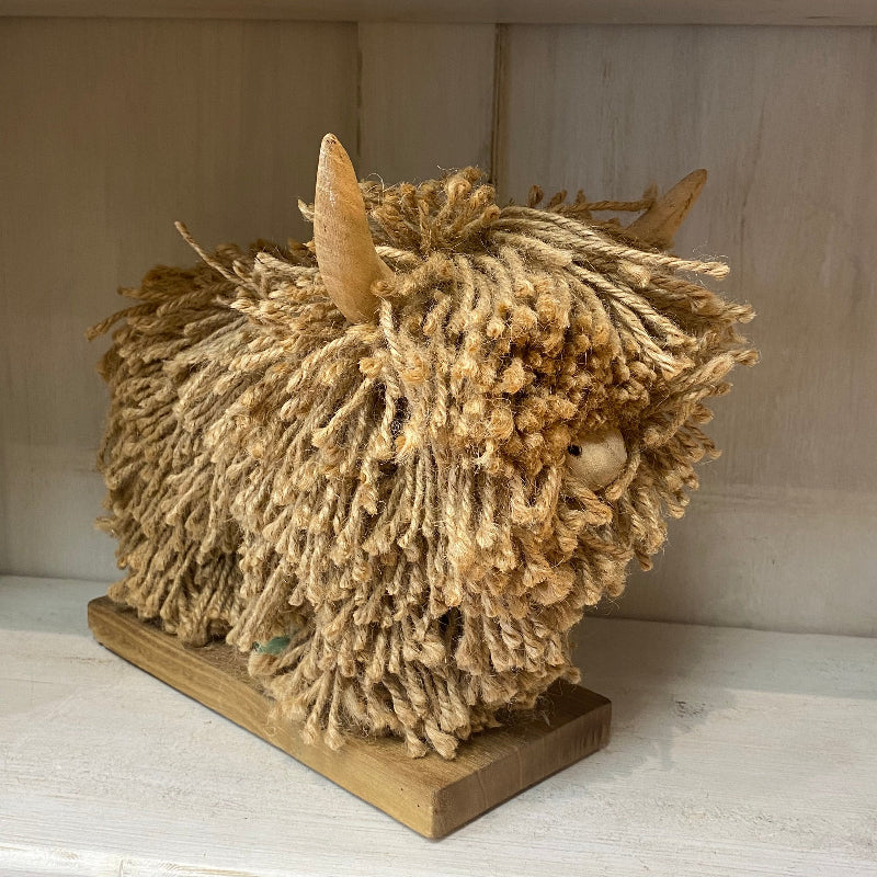 Textured animal head sculpture on a wooden base against a neutral background