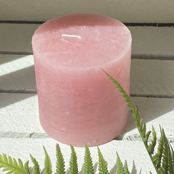 Dusky pink rustic pillar candle from Grand Illusions, showing a tall, textured wax candle with a natural, matte finish.