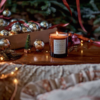 Scented candle by Plum & Ashby featuring cedarwood and pine needles, with a warm, rustic design perfect for holiday ambiance.