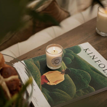 Freckleface luxury mini scented candle in bergamot and verbena with a decorative glass holder and a lit wick.
