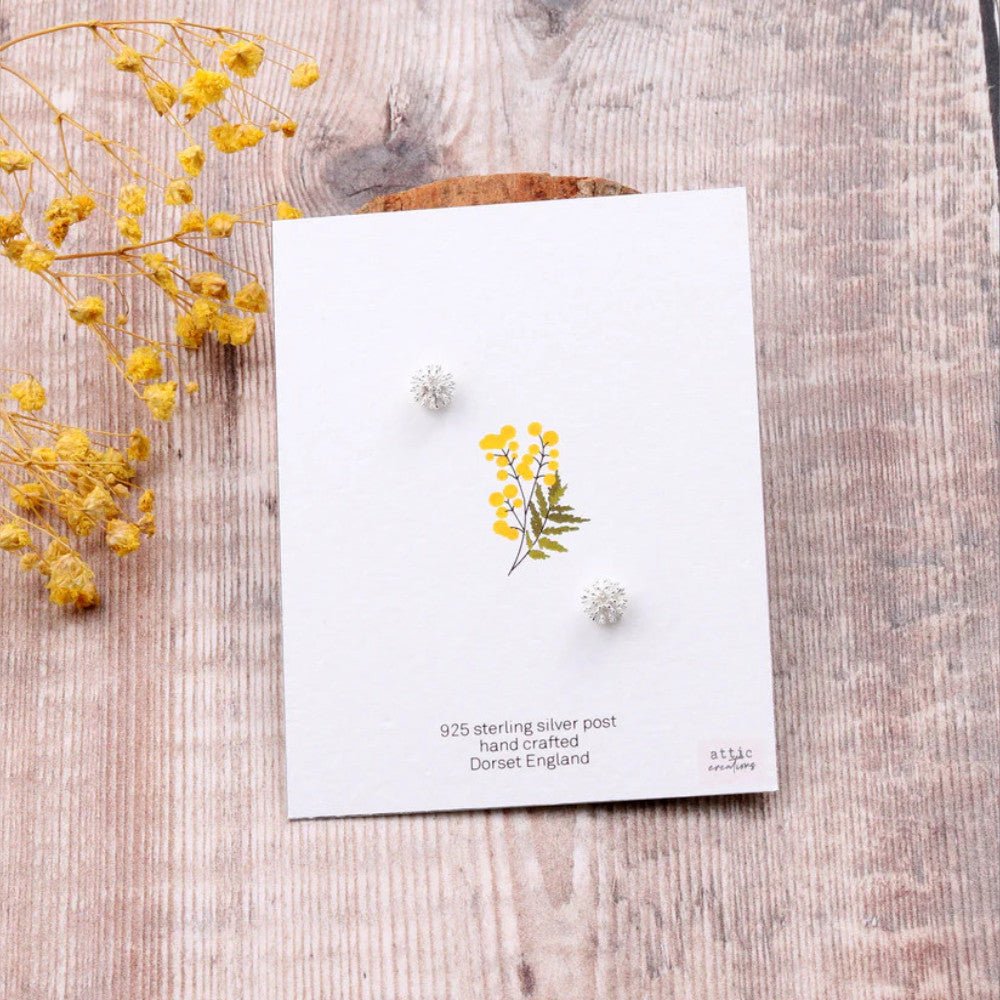 Silver earrings featuring furry ball and flower design by Attic Creations, with intricate floral and textured furry ball details.