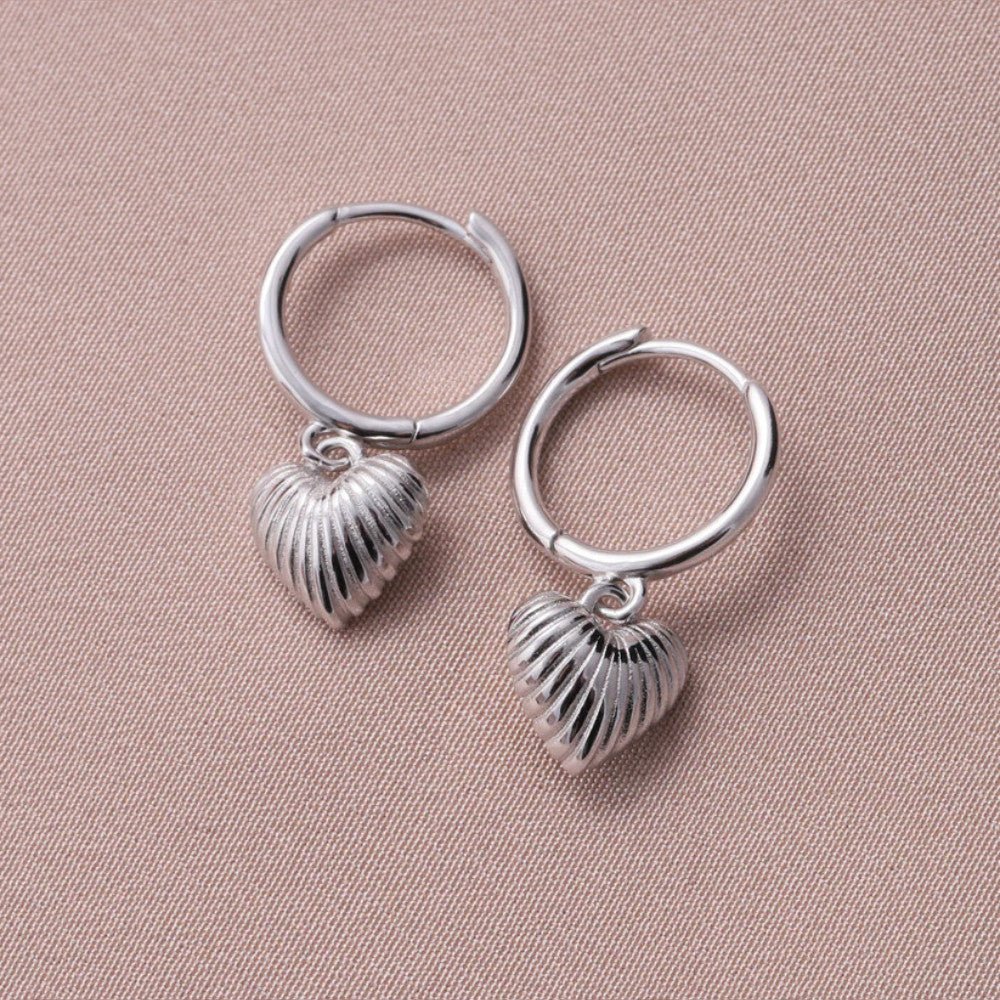 Silver hoop earrings with heart-shaped debossed detail by Attic Creations, showcasing a stylish and intricate design.