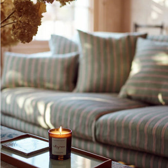 Plum & Ashby scented candle on a sitting room table, creating a cozy ambiance with a simple glass holder.
