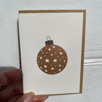 Black and gold stars-themed greeting card from Penguin Ink featuring a festive bauble design.