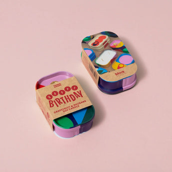 Block Design scented candle in a tin with happy birthday grapefruit and rhubarb scent, featuring colorful floral and fruit illustrations.