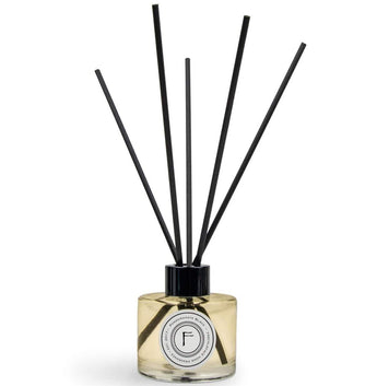 Freckleface Pomegranate Black Reed Diffuser with black and gold decorative reeds in a clear glass bottle.