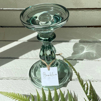 Sea-glass candle holder by Grand Illusions, featuring a smooth, transparent glass design with a hollow center for candles.