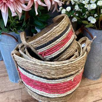 Medium natural and rose-colored wicker basket made of corn and straw, ideal for storage or decorative use.