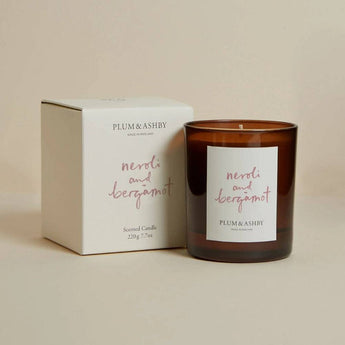 Plum & Ashby Neroli & Bergamot scented candle in a glass jar with a burning wick, showcasing a fresh citrus fragrance.