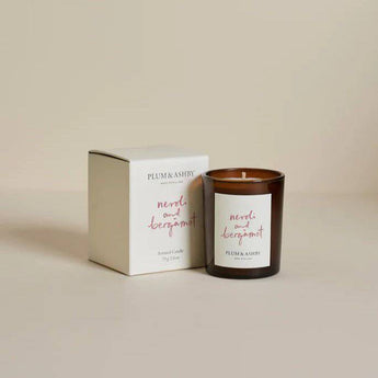 Plum & Ashby Neroli & Bergamot scented votive candle with a glass holder, showcasing a smooth, elegant design and warm candle flame.