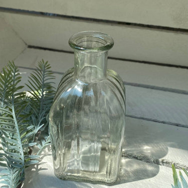 Four assorted glass square bottle vases with unique designs, perfect for modern floral arrangements, by Grand Illusions.