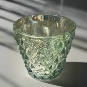 Antiqued silver tea light holder from Grand Illusions featuring a decorative, vintage-style candle holder for ambient lighting.