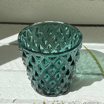 Emerald glass tea light holder from Grand Illusions, elegant candle holder with a vibrant green hue and decorative design.
